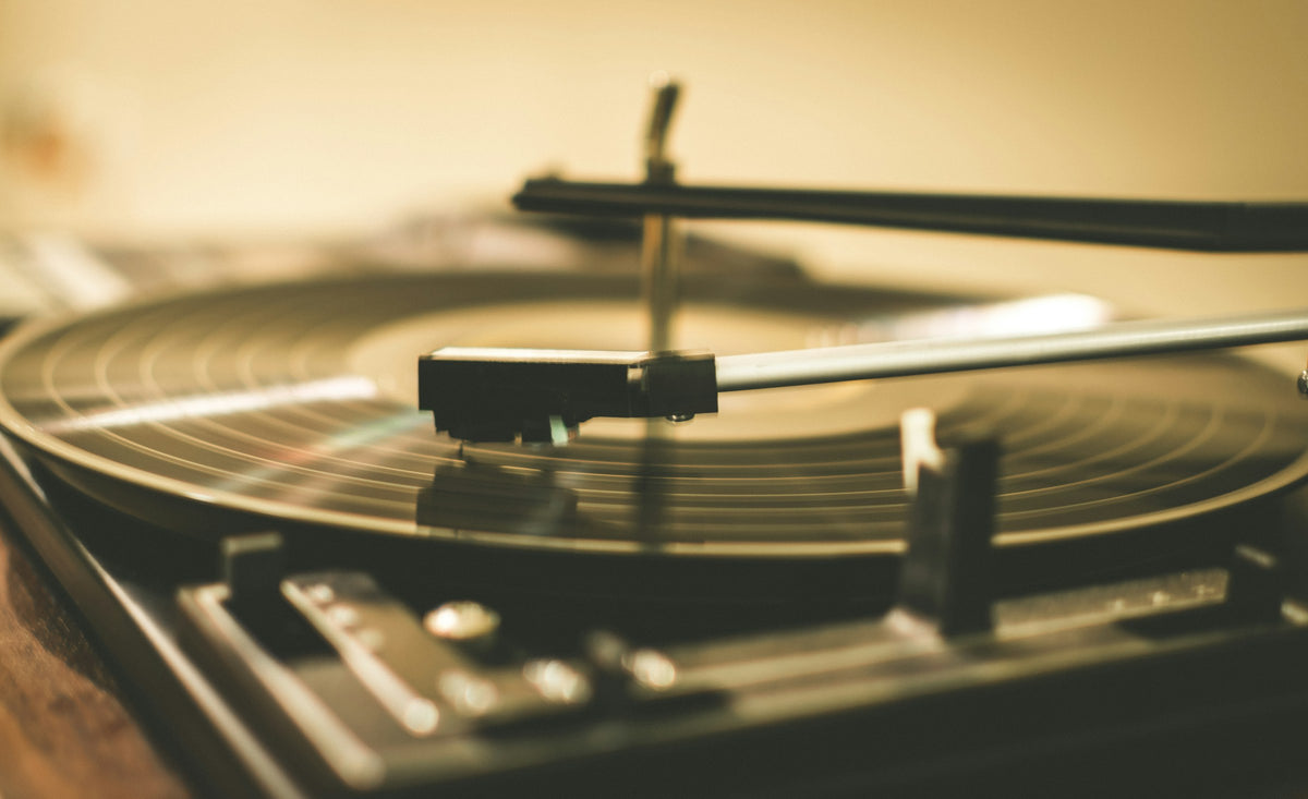 Una púa apoyada sobre un vinilo que gira, en luz cálida